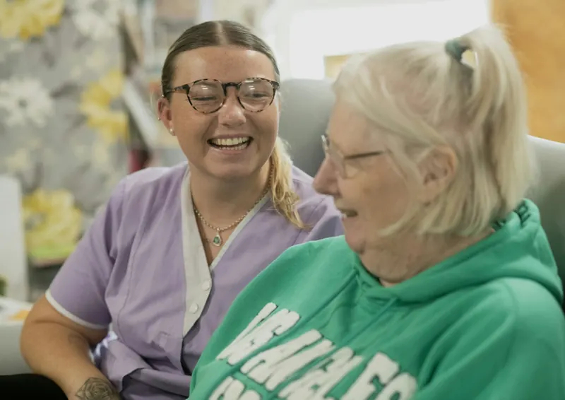 Caregiver and older woman laughing together