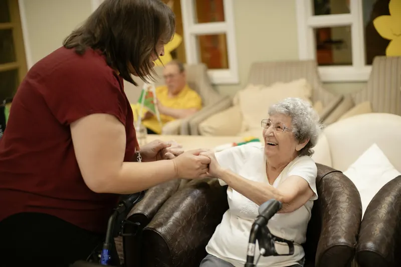 Caregiver holding hands with an older woman using a walker