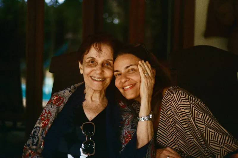Adult daughter and her elderly mother smiling together at home