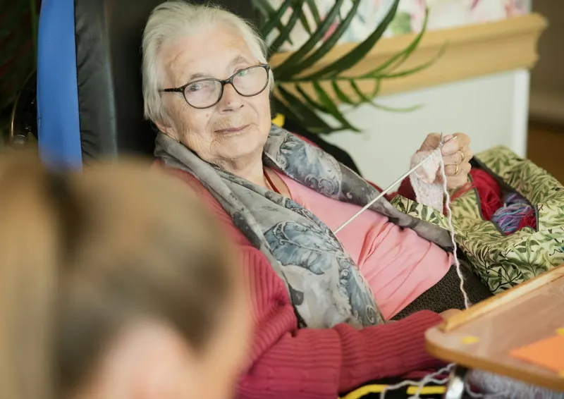 Older woman knitting and smiling
