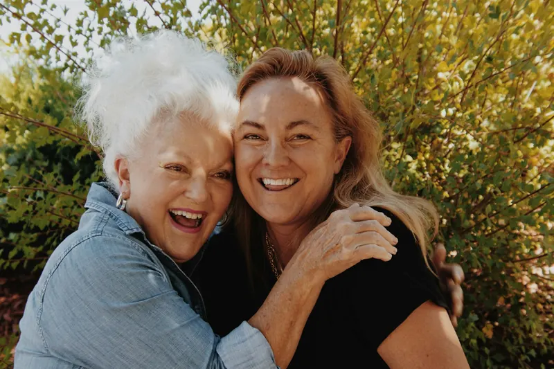 Older woman and her adult daughter hugging outdoors